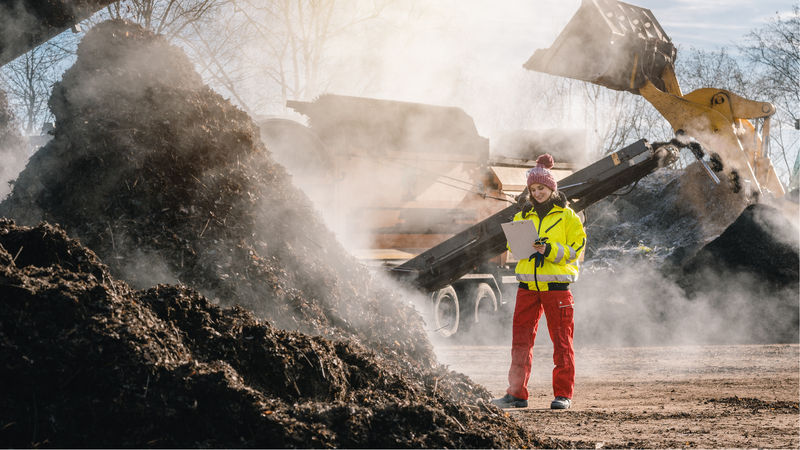 Femme avec un presse-papiers dans une usine de compost industriel